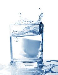 Ice in glass of water with splash on white background.