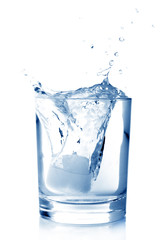Ice in glass of water with splash on white background.