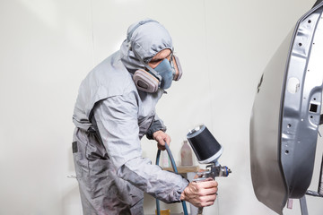 Car body painter spraying paint on bodywork parts