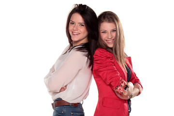 Two smiling girl friends or sisters pose with arms crossed