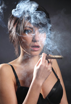 Hot sexy woman with bra smoking cigar. Shrouded in smoke