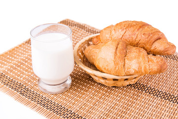 Fresh and tasty French croissants in a basket with glass of milk