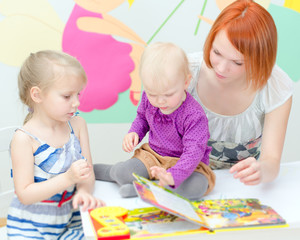 Fototapeta premium Mother and her daughters reading a book