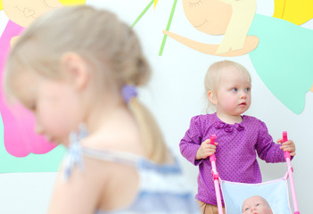 Baby girl with buggy in kindergarten