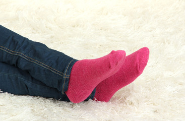 Female legs in colorful socks on  white carpet background