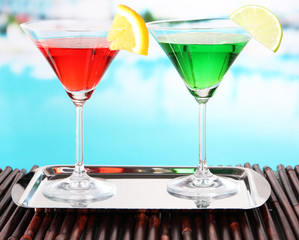 Glasses of cocktails on table near pool