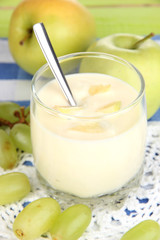 Delicious yogurt in glass with fruit on blue tablecloth