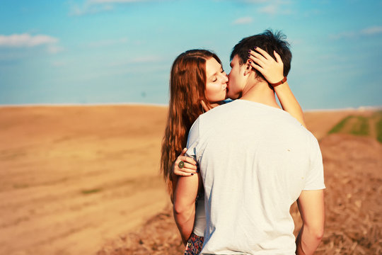 Young attractive couple in love kissing in summer in field