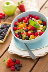 Obstsalat in blauer Schüssel auf Holzuntergrund