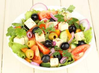 Fresh salad in plate on wooden table