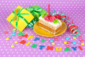 Colorful birthday cake with candle and gifts on pink background