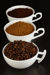 Different types of coffee in three cups on wooden table