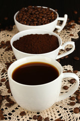 Different types of coffee in three cups on wooden table