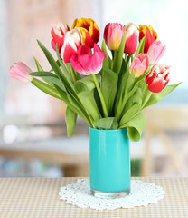 Beautiful tulips in bucket on table in room