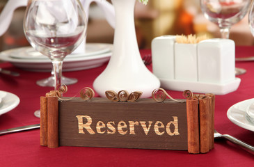 Reserved sign on restaurant table with empty dishes and glasses