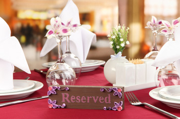 Reserved sign on restaurant table with empty dishes and glasses