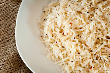 Cooked rice on a white plate jute background