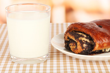 Poppy roll and glass of milk on room background