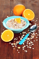 Useful oatmeal in bowl with fruit on wooden table close-up