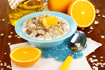 Useful oatmeal in bowl with fruit on wooden table close-up