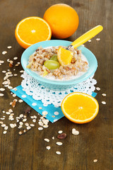 Useful oatmeal in bowl with fruit on wooden table close-up