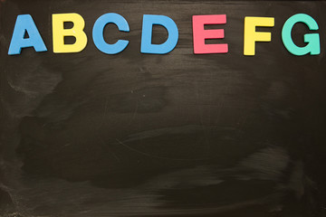 Alphabet magnets stuck on blackboard up to letter g