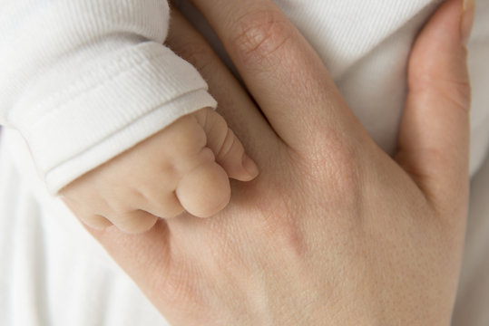 Eine junge Mutter hält zärtlich die kleine Hand ihres Säuglings