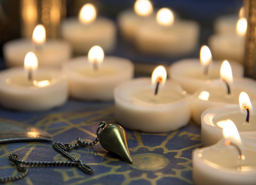 Mystische Szene mit Kerzen und Pendel