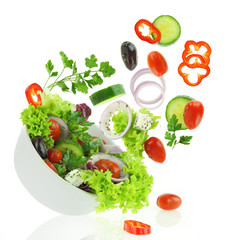 Verse gemengde groenten die in een kom salade vallen