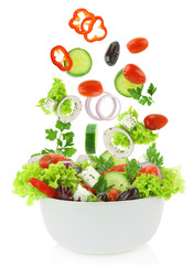 Fresh mixed vegetables falling into a bowl of salad