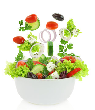 Fresh mixed vegetables falling into a bowl of salad
