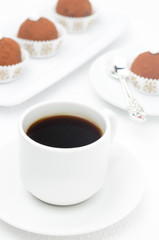 cup of coffee and a little chocolate cakes in the background