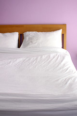 white bed with light purple wall in the morning