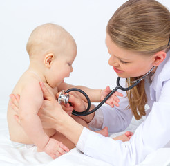 Smiling baby playing with stethoscope of doctor therapist
