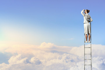 Businesswoman standing on ladder