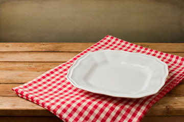 Empty white plate on tablecloth on wooden vintage table