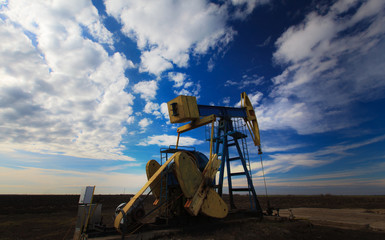 Operating oil well profiled on dramatic cloudy sky