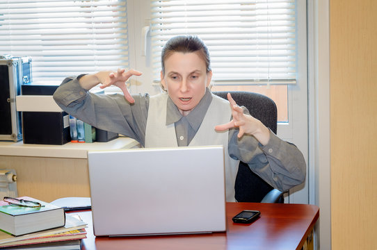 A fifty years old woman very angry with the modern technology is  raging against the computer in office