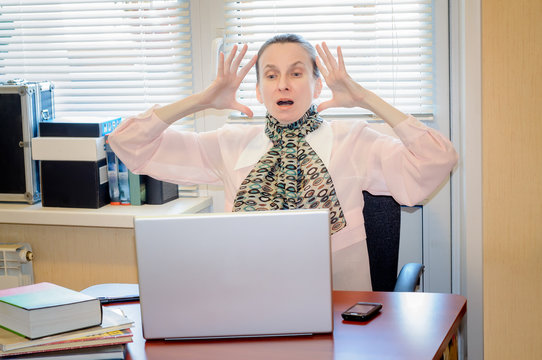 A fifty years old woman very angry with the modern technology is  raging against the computer in office