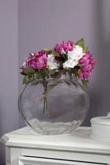 artivicial pink and white peony in glass vase standing on table