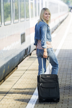 Frau mit Koffer auf dem Bahnsteig
