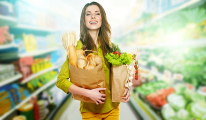 Young woman holding a grocery bag full of bread