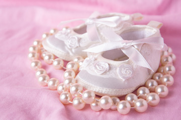 White baby booties with string of pearls