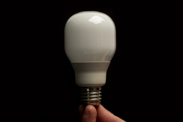 Man holding economic light bulb in his fingertips close up