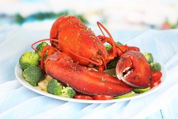 Red lobster on platter with vegetables on table close-up