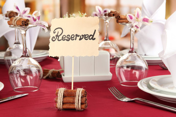 Reserved sign on restaurant table with empty dishes and glasses
