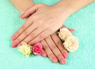 Woman hands with pink manicure and flowers, on color background