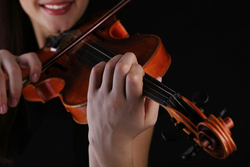 Musician playing violin on black background