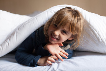 Bimba che gioca sotto il piumone