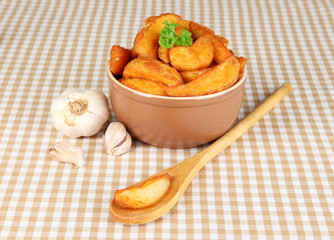 Appetizing village potatoes in bowl on beige tablecloth